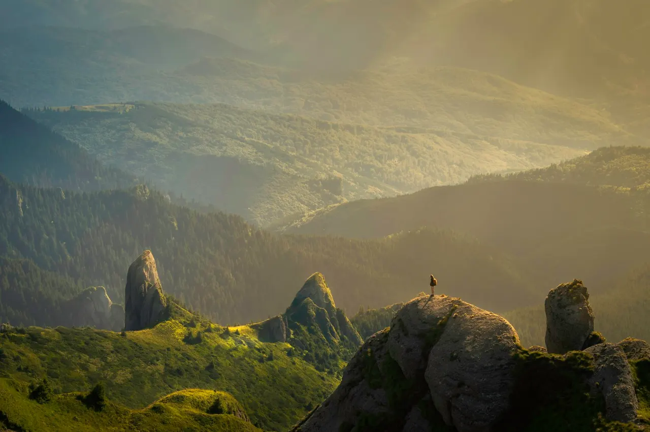 Sunlight breaking through clouds over a dramatic mountain landscape